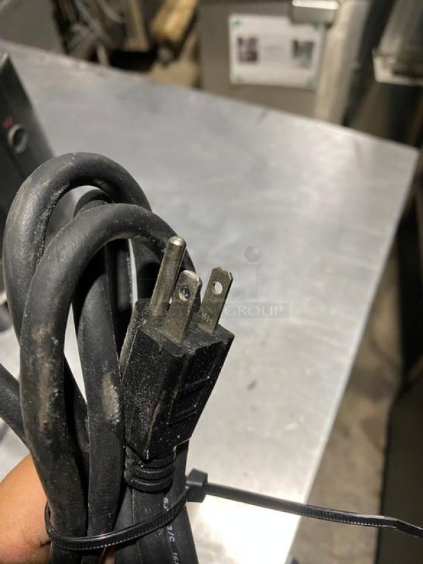 Black power cord with two-prong plug, slightly worn condition, secured with a zip tie.