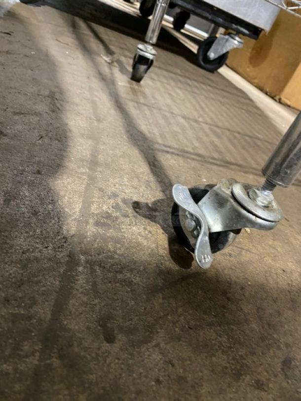 Metal cart with swivel caster wheels on a concrete floor; appears in used condition.