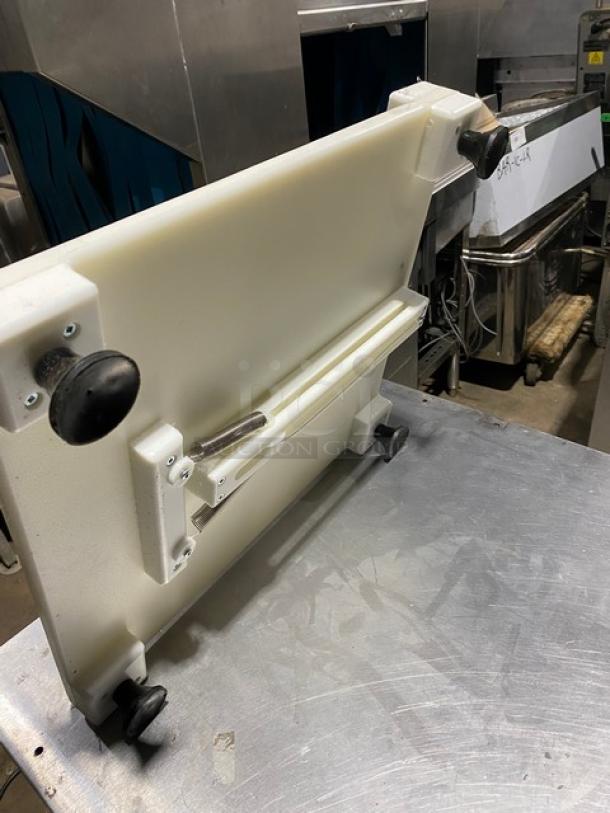 Commercial meat slicer accessory, white plastic with metal components, adjustable knobs, in used condition.