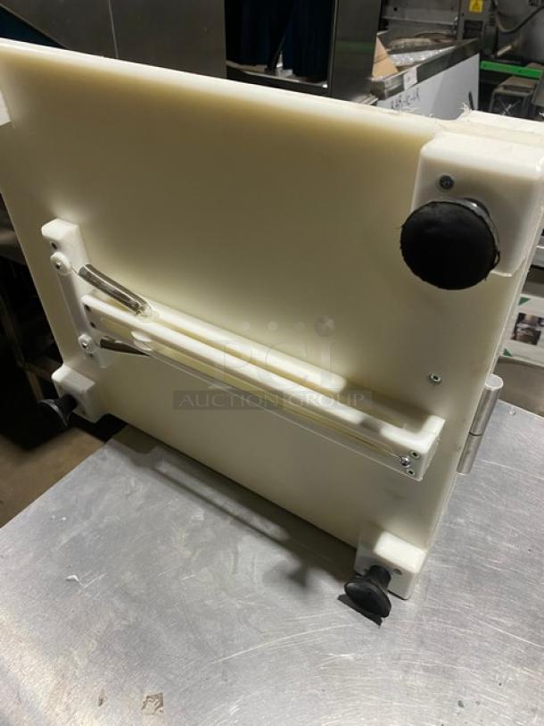 White commercial kitchen slicer in good condition, featuring a black knob, sturdy base, and adjustable components.