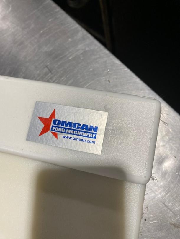 White Omcan cutting board with company logo. Sturdy plastic construction, new condition. Visible brand label, Omcan Food Machinery.