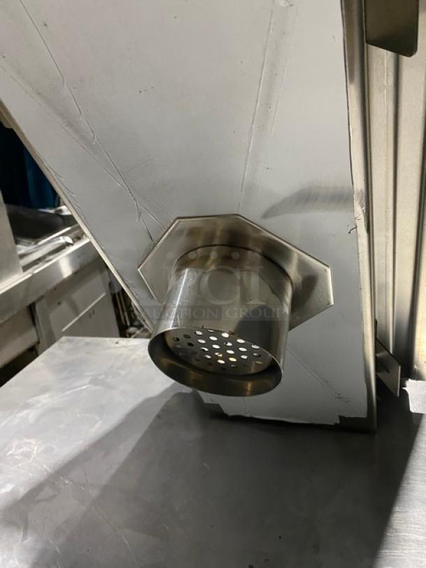 Stainless steel industrial discharge chute with perforated outlet, mounted on metal equipment. Good condition, no visible markings.