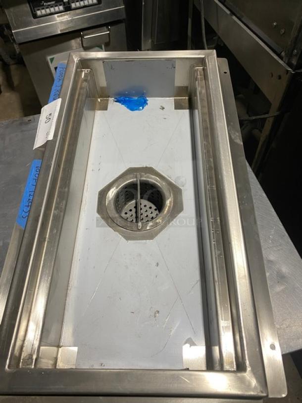 Stainless steel drain assembly, rectangular, with central strainer. Slight wear visible. Label reads "50."