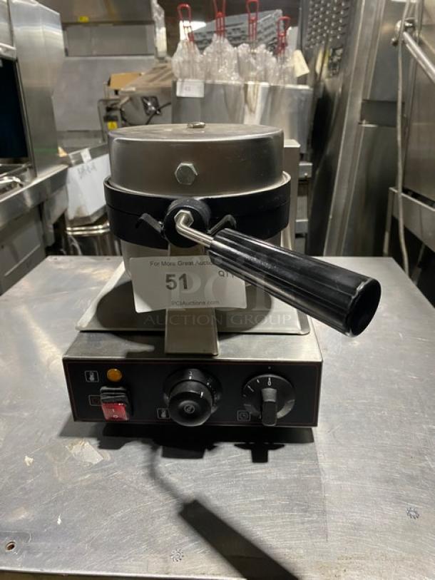 Commercial waffle maker in stainless steel with a black handle, control knobs, and labeled auction number 51. Good condition.