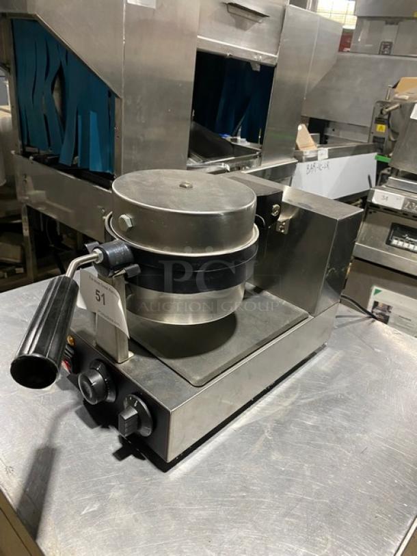 Commercial waffle maker with stainless steel body, black handle, and dual control knobs. Unit shows tag labeled "51". Appears in used condition.