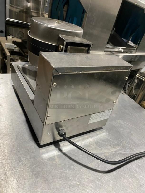 Commercial stainless steel waffle maker, used condition, with power cord; label shows specifications.
