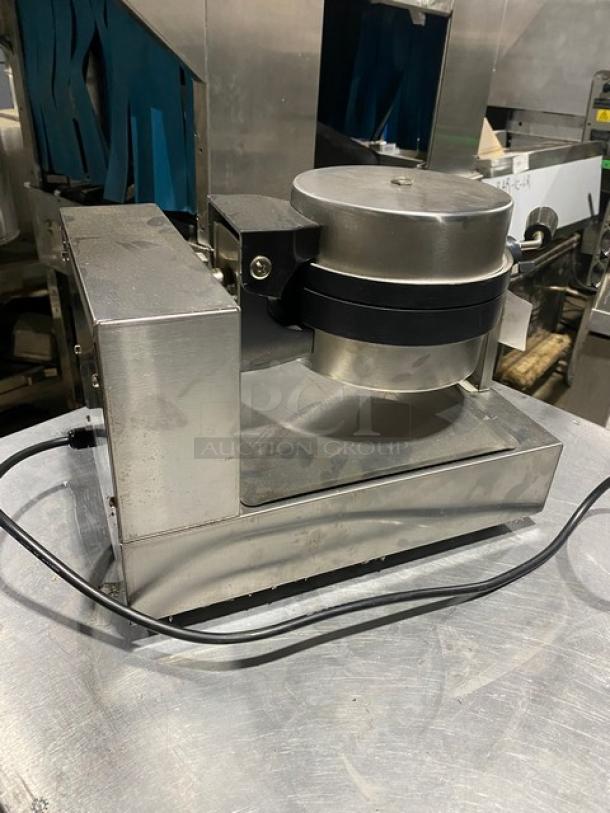 Stainless steel commercial waffle maker, used condition, with visible power cord, on a metal countertop.