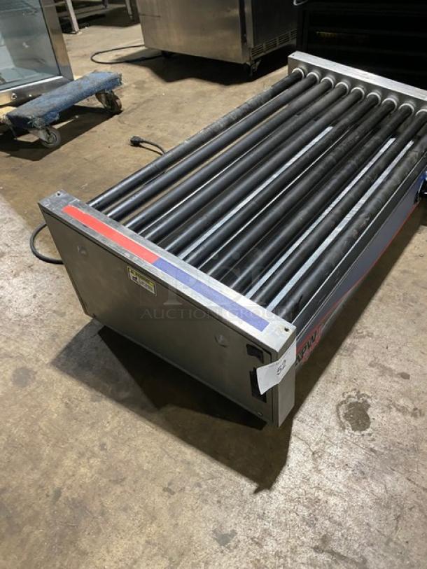 Industrial roller conveyor with black rollers, metal frame, and visible wear. Markings indicate brand and model details.