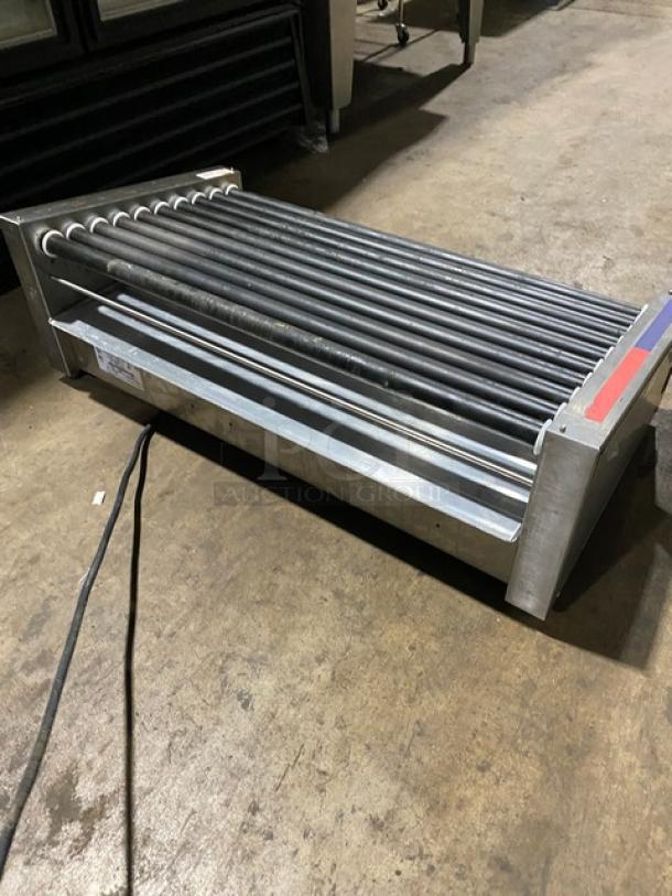 Industrial stainless steel roller grill with 10 rollers, slight wear, visible power cord.