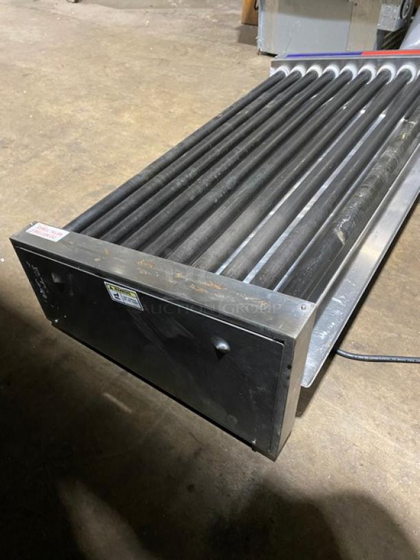 Industrial conveyor roller assembly, metal frame, visible wear, includes safety and model labels, used condition.