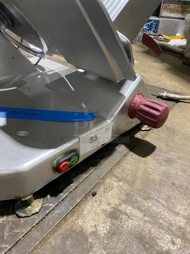 Commercial meat slicer with red adjustment knob, on/off buttons, blue auction tape marked "Auction," and lot label "53."