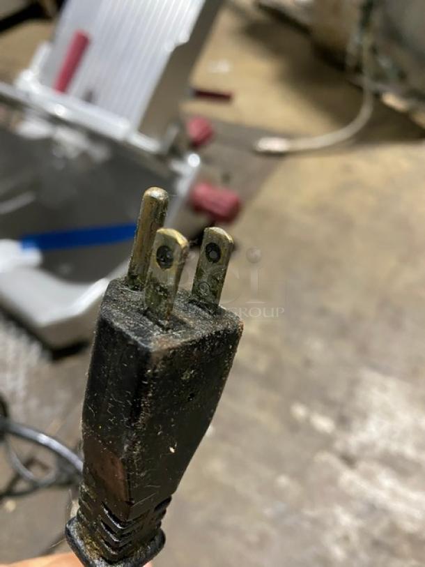 Close-up of a worn three-prong electrical plug with visible dirt and corrosion on pins, indicating heavy use or age.