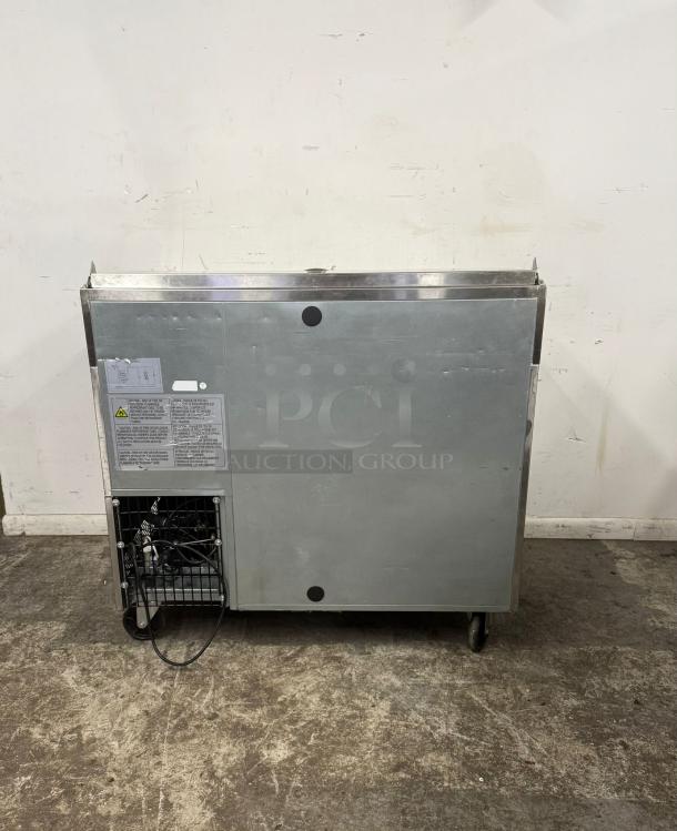 Commercial stainless steel refrigerator unit, used condition, visible ventilation and power cord, safety instruction labels attached.