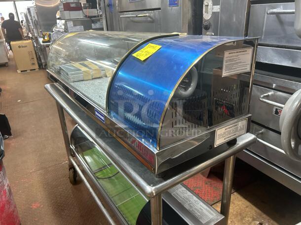 Commercial refrigerated display case with curved glass top, stainless steel finish, and visible maintenance labels.