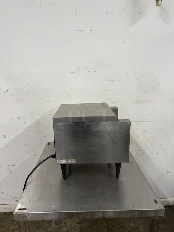 Stainless steel commercial toaster, rectangular, cord attached, good condition, placed on metal surface.