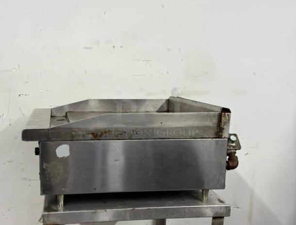 Stainless steel commercial griddle, used condition, featuring rust spots and tarnish on the surface, with adjustable legs.