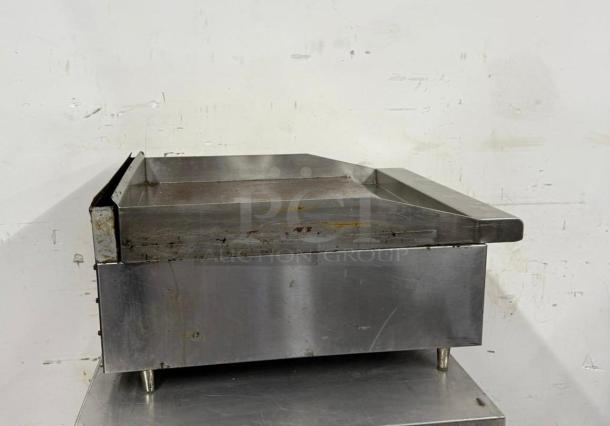 Stainless steel commercial griddle with visible wear and rust marks, suitable for restaurant use. Measures approximately 3 feet wide.