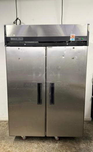 Commercial stainless steel Maxx Cold refrigerator, two-door, large capacity, visible wear, wheels attached for mobility.