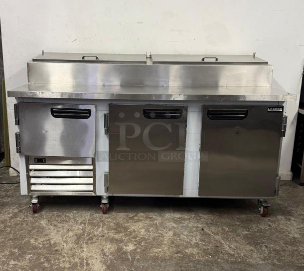Stainless steel Leader commercial prep refrigerator, double doors, casters, slight surface wear, ideal for restaurant use.