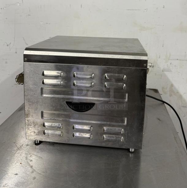 Stainless steel commercial toaster oven with vented sides, in used condition, featuring a power cord on a metal surface.