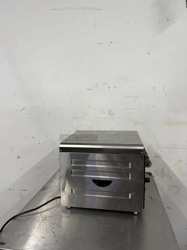 Stainless steel commercial toaster oven, side view. Power cord attached. Good condition, minor surface scratches visible.