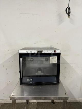Weston countertop food warmer in good condition. Features digital controls, glass front, and visible caution label.