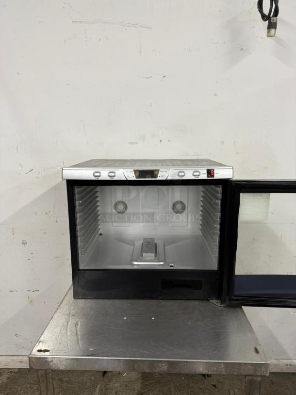 Small stainless steel commercial refrigerator, open door, digital controls, interior shelves, gently used condition.