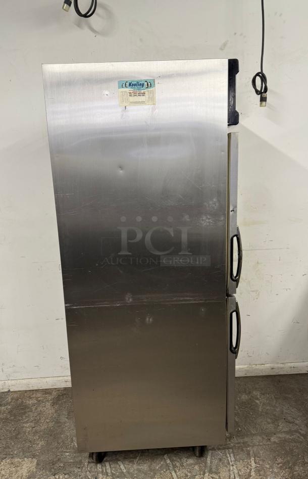 Stainless steel commercial refrigerator with dual doors, visible dents, and "Kooling" label indicating temperature settings.