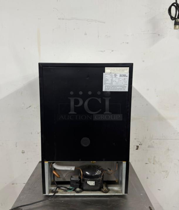 Black commercial ice machine with visible compressor, maintenance label, and caution notice. Good condition.