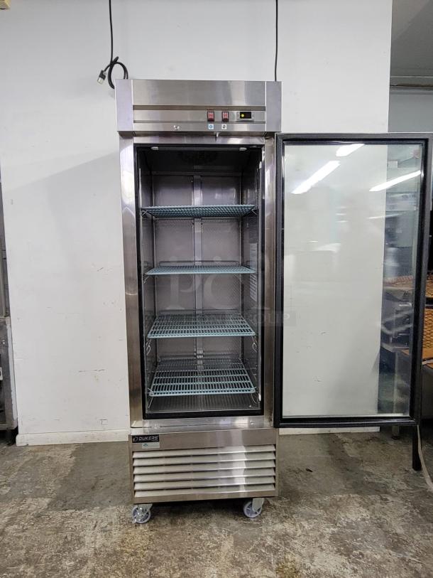 Commercial stainless steel refrigerator on wheels, three wire shelves, transparent door, digital controls. Model: Dukers D28R-GS. Excellent condition.