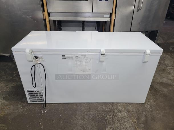 Large white chest freezer in good condition. Features three secure latches, power cord, and manufacturer label with specifications.
