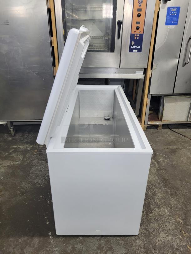 White chest freezer with open lid, clean interior, and sturdy build. Used condition. No visible markings or tags.