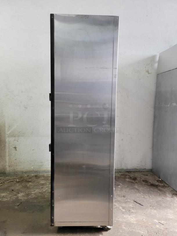 Tall stainless steel cabinet on casters, side view. Industrial design, slightly worn condition, suitable for storage.
