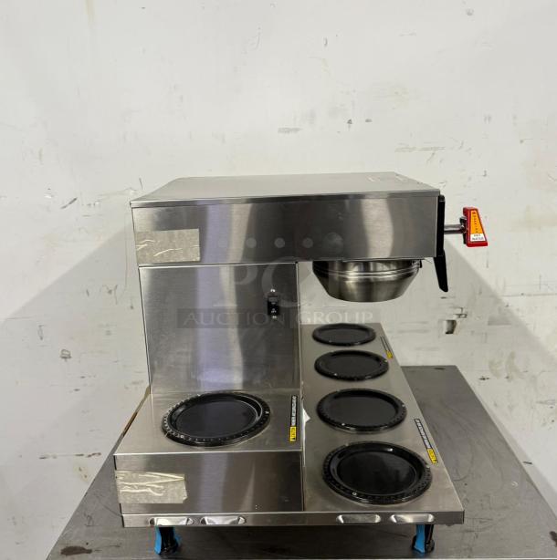 Stainless steel commercial coffee maker with four warming plates, used condition. Includes power switch and labeling.