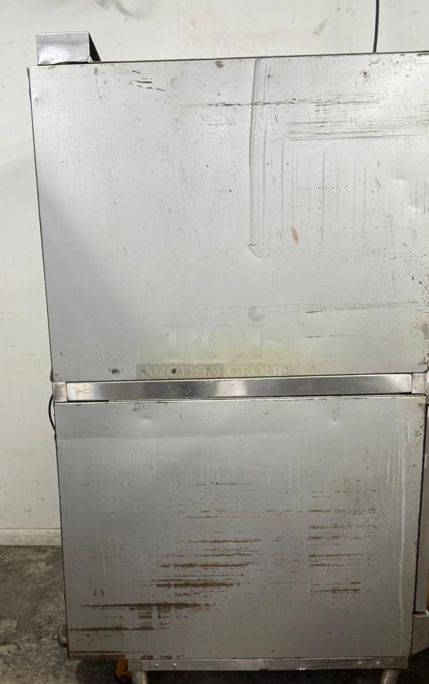 Commercial stainless steel refrigerator, used condition, visible scratches and wear, two doors, industrial style handle.