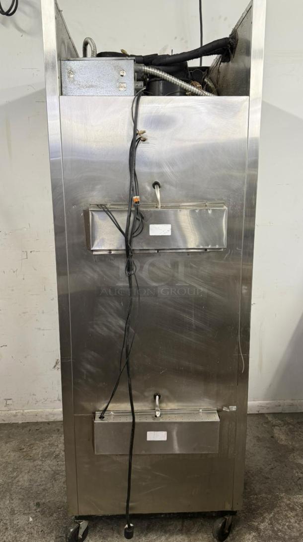 Commercial stainless steel ice cream machine, upright, on wheels. Features visible piping and wiring. Condition: used.