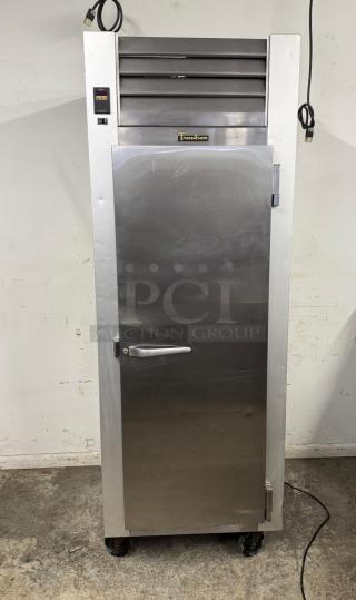 Traulsen commercial stainless steel refrigerator, single door, with top ventilation, wheels, and power cord, showing slight wear.