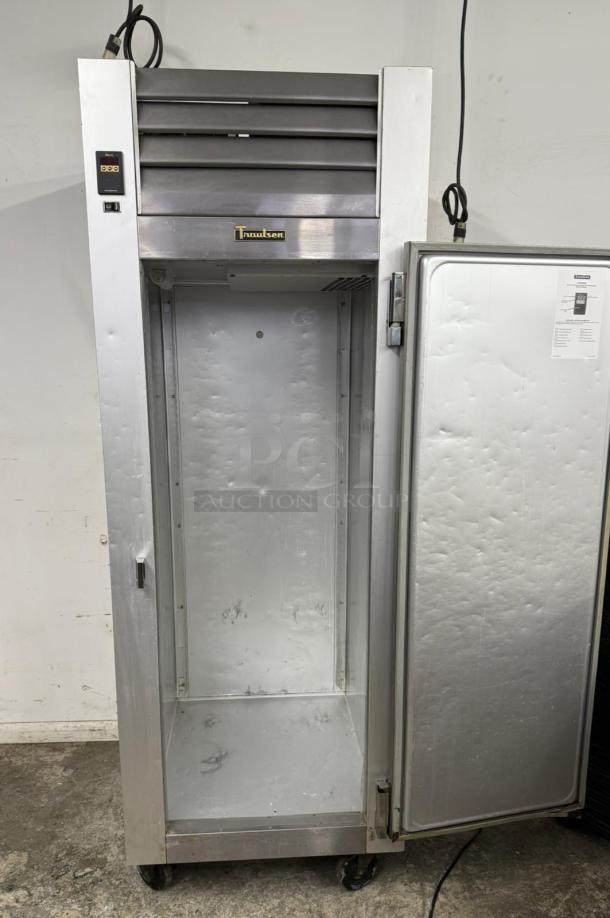 Traulsen commercial refrigerator, stainless steel, single door, empty interior, visible wear, branded label on front.