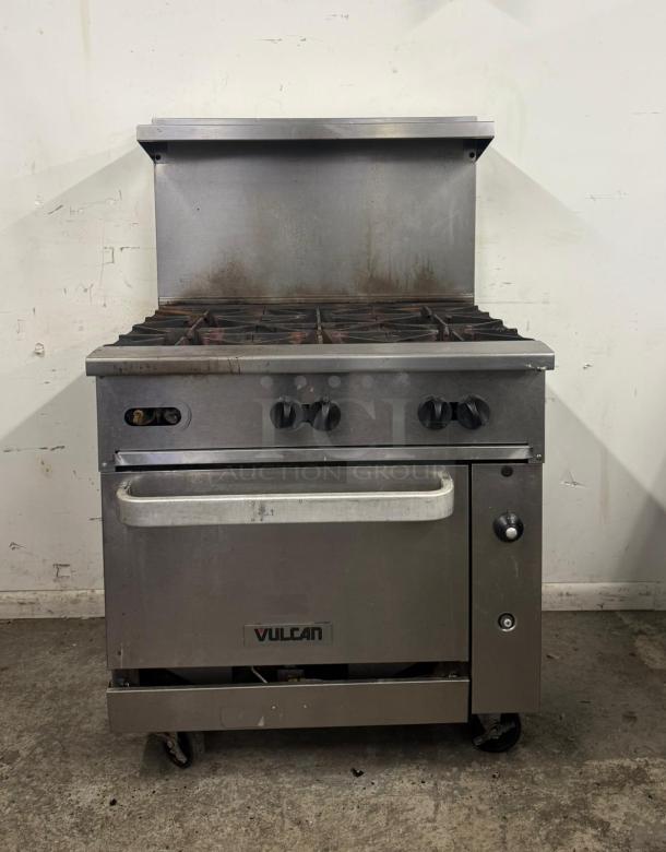 Vulcan commercial stove with six burners, stainless steel, some wear marks, functional knobs, branded front panel.