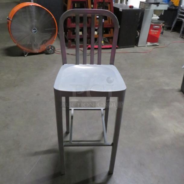 Aluminum bar height patio chair with slatted back and footrest. Sturdy, modern design, good condition. Ideal for outdoor use.