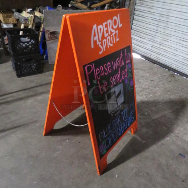 A-Frame sidewalk chalkboard sign, 24x39 inches, orange frame, "Aperol Spritz" branding, reads "Please wait to be seated."