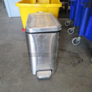 Small stainless steel step trash can, rectangular shape, visible scuff marks, foot pedal mechanism, suitable for compact spaces.