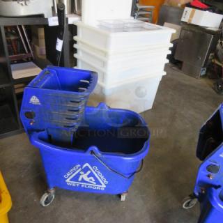 Blue mop bucket with wringer, "Caution Wet Floors" label, on casters for mobility; used condition.