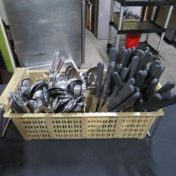 Beige flatware dish rack with assorted silver-colored flatware and black-handled utensils, in good condition.