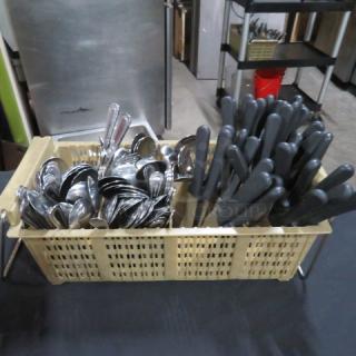 Beige flatware dish rack with assorted silver-colored flatware and black-handled utensils, in good condition.