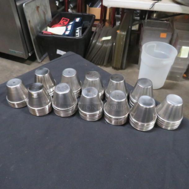 Lot of approximately 110 stainless steel condiment cups, stacked and displayed on a table, in good condition.
