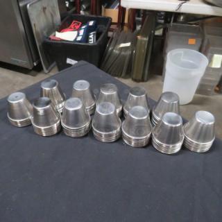 Lot of approximately 110 stainless steel condiment cups, stacked and displayed on a table, in good condition.
