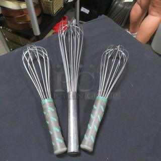 Three assorted stainless steel whisks with gray and teal handles, in good condition, displayed on a table.