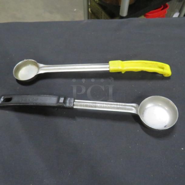 Two assorted spoodles with stainless steel bowls, one with a yellow handle, the other with a black handle, in good condition.