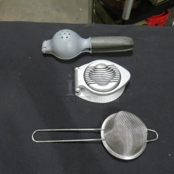 Assorted kitchen utensils: metal lemon squeezer, egg slicer, and wire mesh strainer. Good condition.